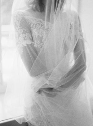 Fine art black and white photo at Graydon Hall of the Cassandra Veil's long blusher wrapped around the bride. The sheer Italian tulle creates a romantic, voluminous effect.