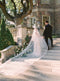 Bride and groom ascending the stone stairs at Graydon Hall. The Cassandra Long Blusher Veil train sweeps dramatically behind the bride. The dramatic Imperial length creates a royal look.