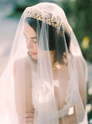 Close-up portrait at Graydon Hall showing the Cassandra Veil's sheer long blusher draped over a bride wearing an ornate gold and pearl wedding tiara.