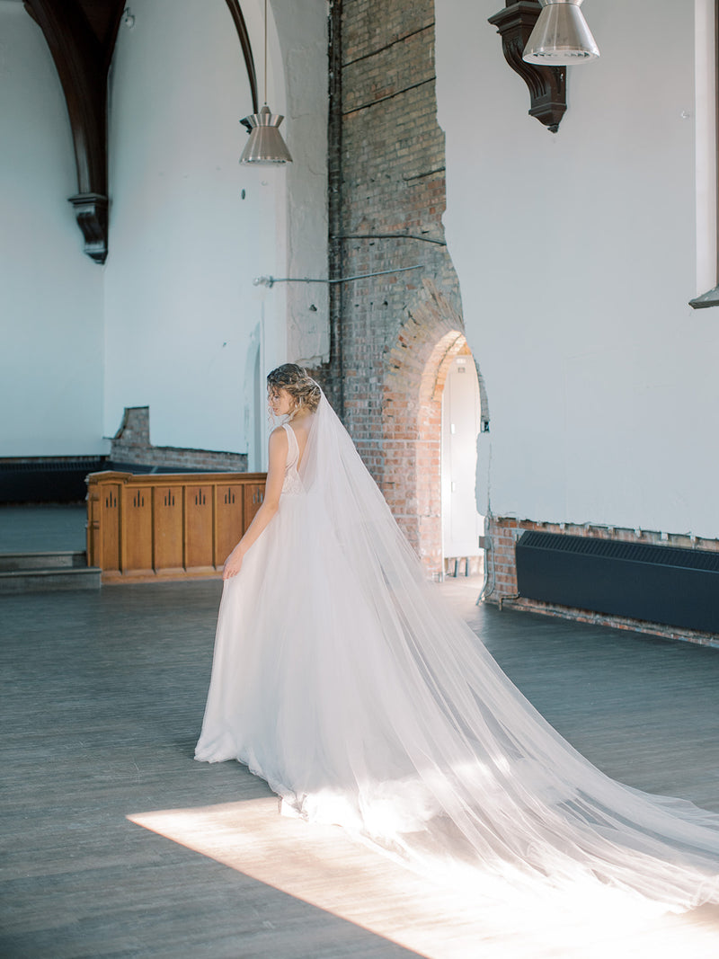 Classic portrait of the bride wearing the Grace Silk Blusher Veil with the blusher at the back, showing the wide train of the veil.
