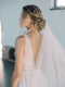 Close profile shot of the bride's head and back, showing her elegant low updo and the Grace silk wedding veil flowing down; blusher opened and worn at the back.