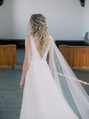 KAJA draped bridal cape veil styled with a lace gown and half up hairstyle.