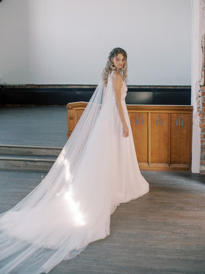 KAJA draped bridal cape veil styled with a lace gown and half up hairstyle.