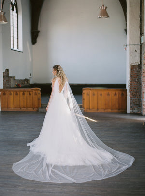 KAJA draped bridal cape veil, extra wide cape train fanned out behind the bride.