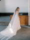KAJA draped bridal cape veil styled with a lace gown and half up hairstyle.