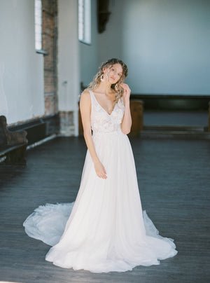 Full-body image of a bride modelling the KYOTO Floral Bridal Earrings and a flowy a-line lace wedding dress in a historic church.