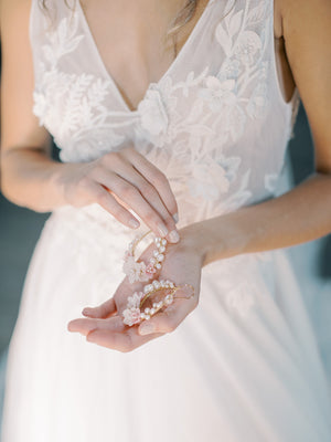Detailed close-up of the KYOTO Floral Bridal Earrings in a bride's hands, featuring pearls, and delicate pink clay flowers.