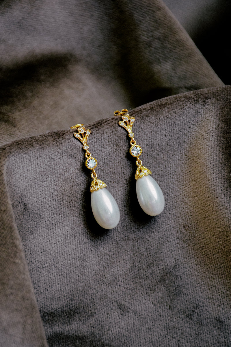 A detailed shot of the LYON pearl drop earrings showing the soft lustre of the teardrop pearl on velvet.