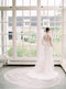 Back view of the bride wearing a fitted lace gown and the Olivia wedding veil. The wide train of the veil is fanned out on the ground behind the bride.