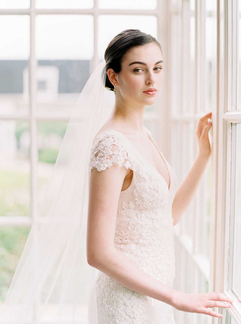 Softly lit close-up of a bride wearing the Olivia wedding veil with a low updo, creating a romantic, timeless look.