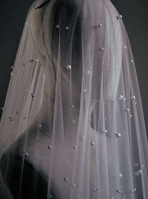 OPERA sheer scattered pearl wedding veil detail shot draped over a mannequin's head and neck.