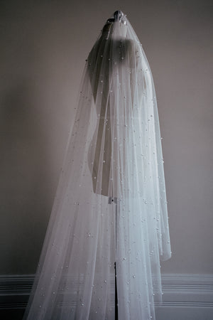 Full length view of the OPERA scattered pearl wedding veil draped on a dress form, showing the length of the blusher. 