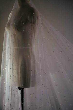 Detailed shot of the sheer OPERA veil on a mannequin, highlighting the pearl embellishment on the blusher.