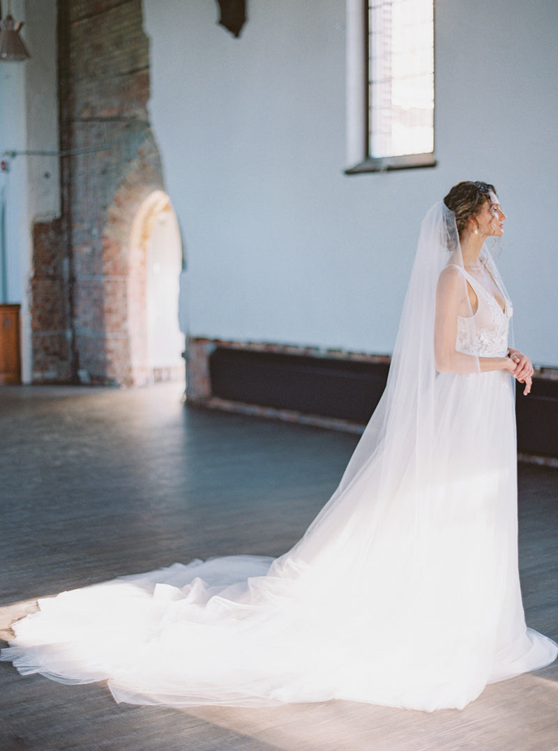 Side view of a bride wearing the voluminous Rosanna veil in grand length.