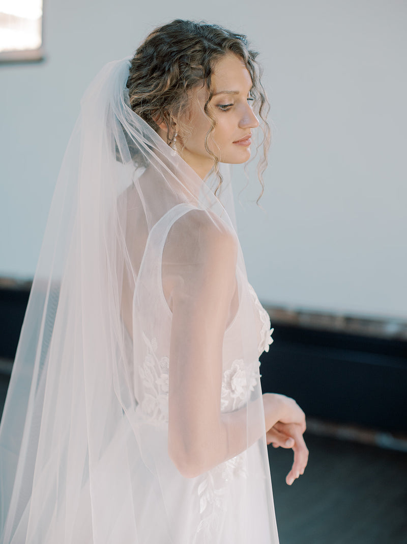 Close-up profile of a bride wearing the ROSANNA full wedding veil styled with a low updo. 