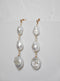 The Tia pearl drop earrings on a textured background. The pearls glow in the light.