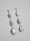 Pair of Tia long drop wedding earrings, showing the graduating size of the baroque freshwater pearls against a textured white background.